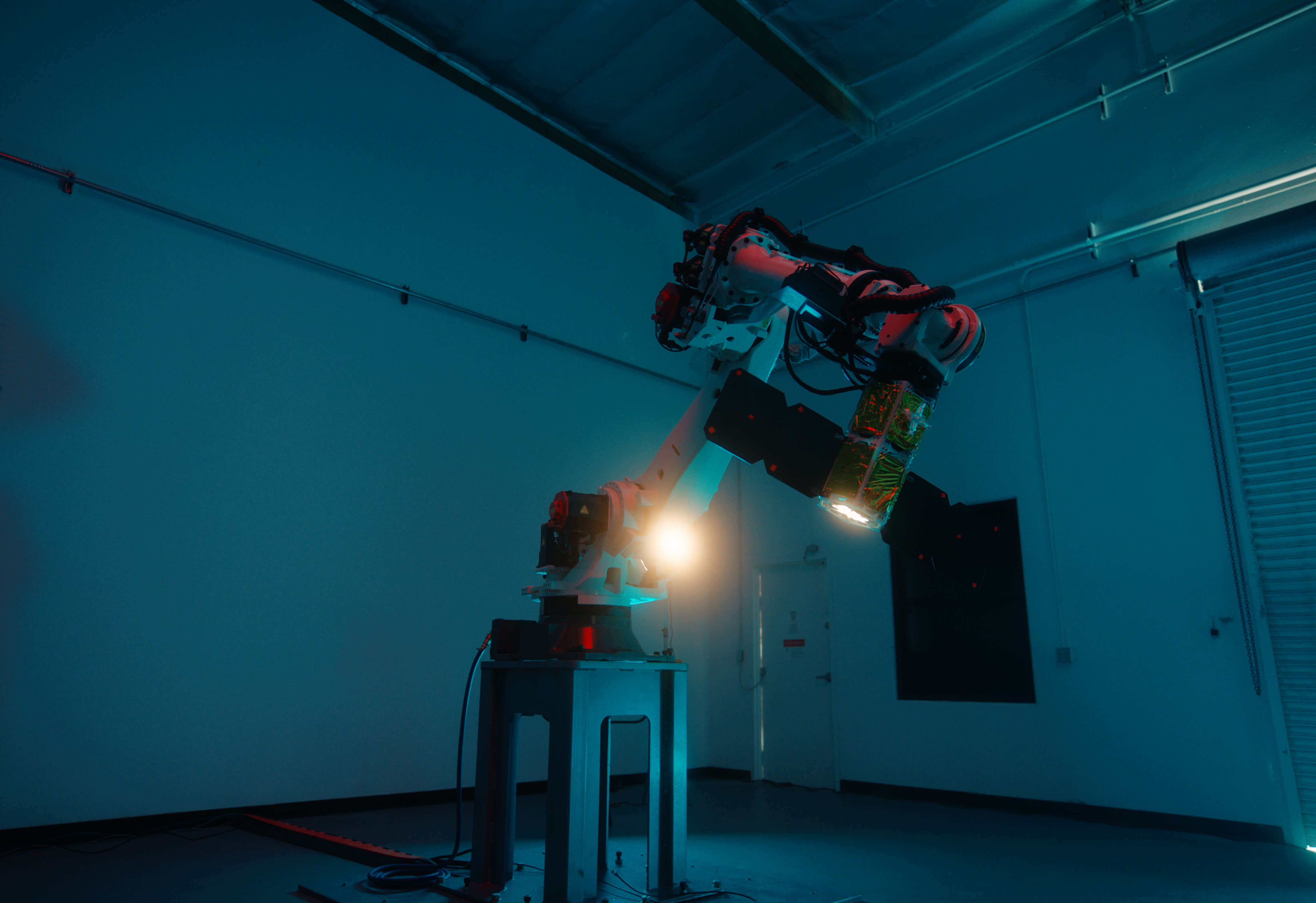 Industrial robotic arm testing spacecraft hardware in Fortastra's blue-lit laboratory